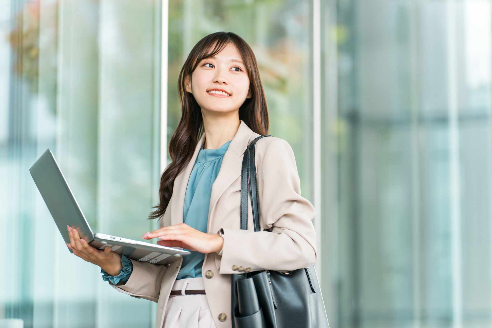 ノートPCを手に前を向いて歩く女性